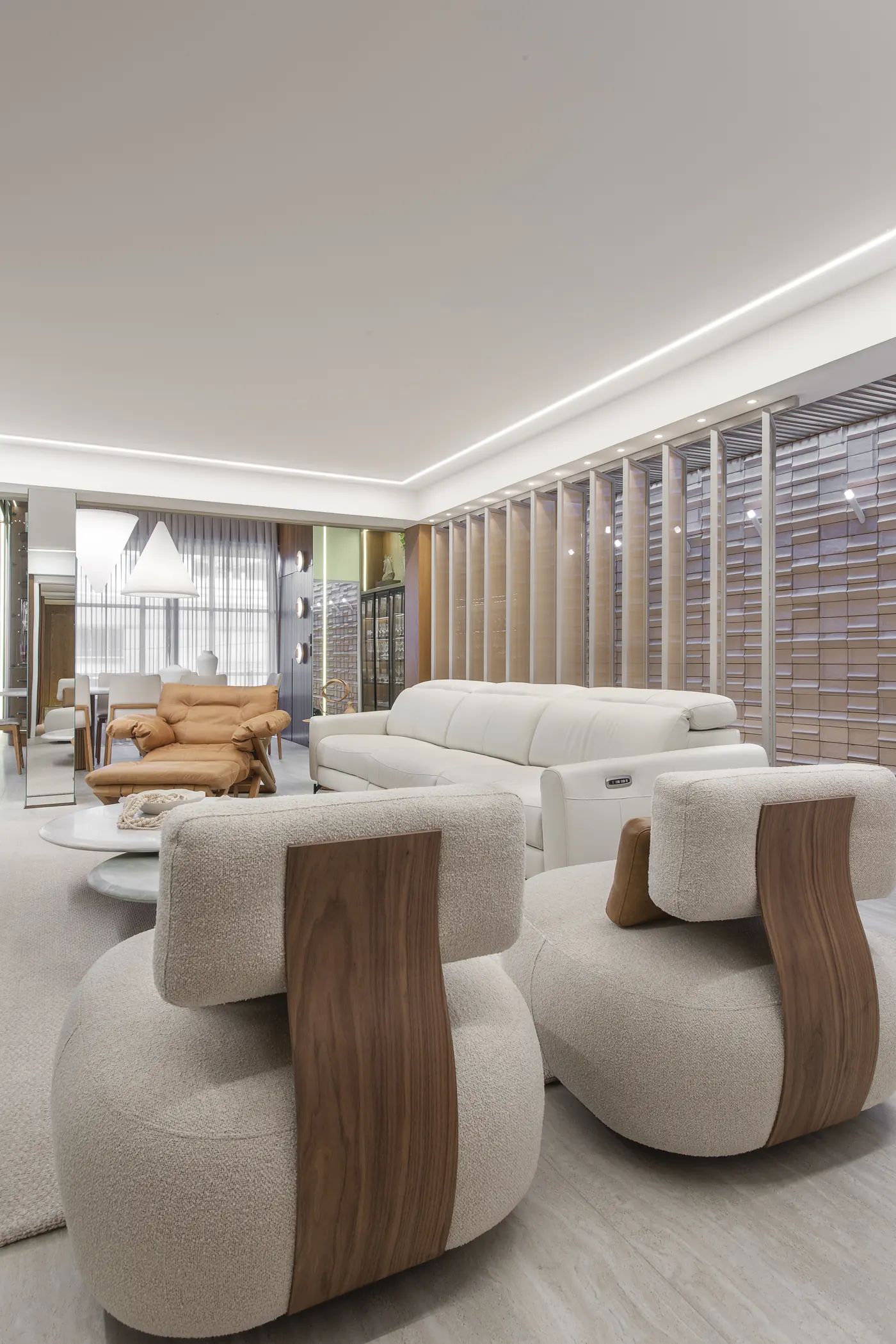 Sala da Bello Traço com poltronas de bouclé e madeira, sofá claro e poltrona de couro caramelo